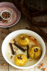 Baked apples with raisins, hazelnuts and cinnamon on wooden background. Rustic style.
