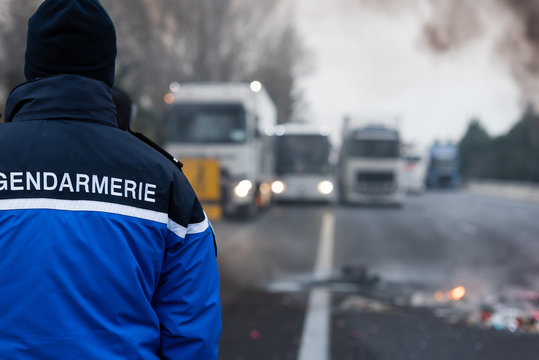 Gendarme de dos face &agrave; des camions bloqu&eacute; sur l'autoroute - Manifestation