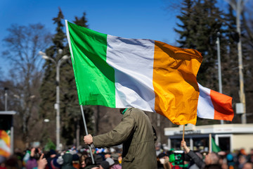 Flag of Ireland close-up in hands of man, on background of crowd people during the celebration of...