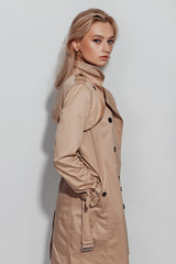 Fashion model in a trench coat, model on a white background