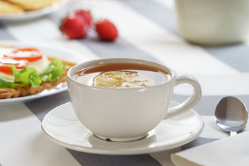 Fresh, tasty breakfast with a sandwich and tea on a light background.