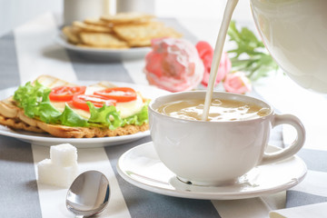 Fresh, tasty breakfast with a sandwich and tea on a light background.