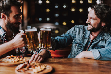 Cheerful friends toasting with drinks while spending time at pub
