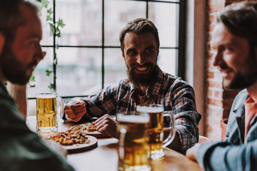Cheerful bearded man spending time with friends at pub