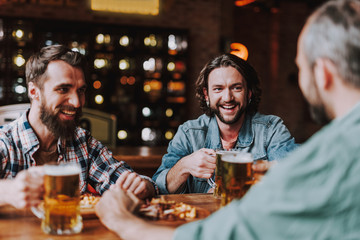 Cheerful friends chatting and enjoying drinks at pub