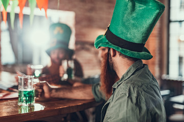 Young man in traditional headwear celebrating Saint Patrick Day at pub