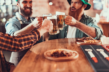 Cheerful friends toasting with mugs of beer