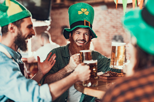 Cheerful young man celebrating Saint Patrick Day with friends in pub - Powered by Adobe