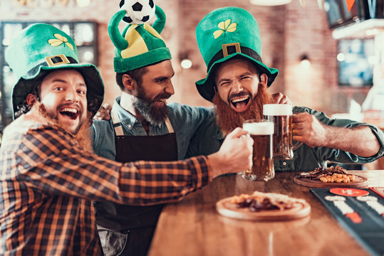 Cheerful friends celebrating football championship and Saint Patrick Day in pub