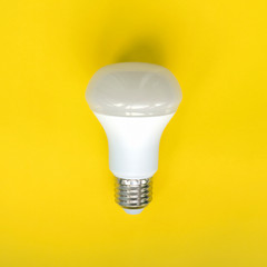 Light bulb on yellow background. Fluorescent,  energy savings led lamp.