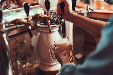 Bartender filling glass with lager beer in pub