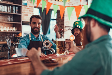Cheerful barman in apron serving drinks to visitors