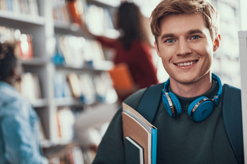Cheerful Caucasian young man with headphones standing and smiling