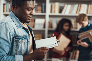 Calm Afro-American student thoughtfully looking at his notes