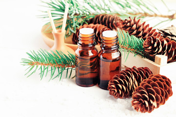 Essential oils wood scents. Natural pine cones and fir tree branches, dropper bottles, on white table.