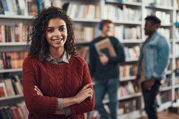 Waist up of confident lady smiling while fellow students standing behind her