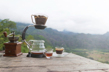 Morning cup of coffee with Rotary Coffee Grinder on the wooden table with mountain background at sunrise and sea of mist, image with copy space.