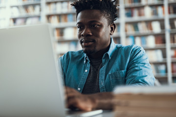 Close up of confident student sitting and working on his laptop