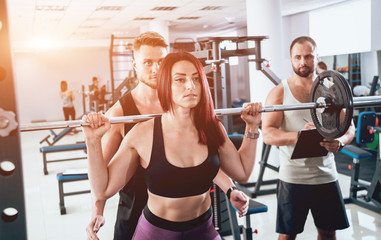 Fototapeta premium Fitness woman exercising with fitness trainer in gym. Personal fitness instructor.