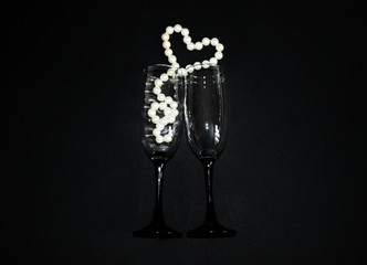 Wine glass. Decoration of white pearls on black background. Heart-shaped decoration.  Valentine's day layout. Declaration of love.