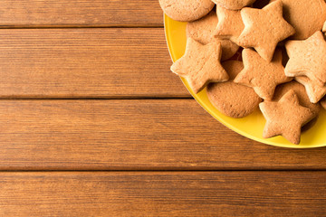 Top view of freshly made cookies in a yellow plate on a wooden table. Empty space for text
