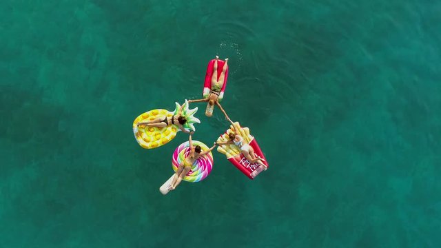 Aerial view group of women holding hands on inflatable mattress on Atokos.