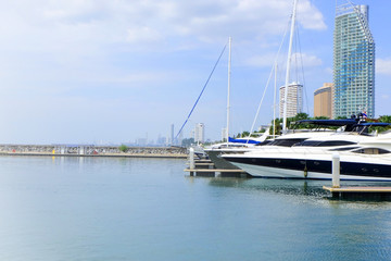 Fototapeta premium Yacht lie up in the port on seaside with blue sky, boat on the coast line, View on the sea shore, Yacht park on riverside, Bright clouds sky on sea in Thailand
