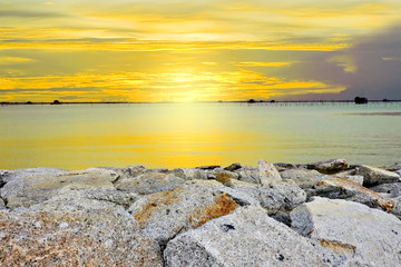 Sunset above the sea with rock on coast line