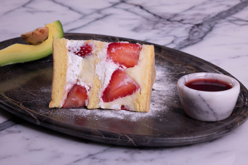 Strawberry cake and alligator pear in marble plate on marble table