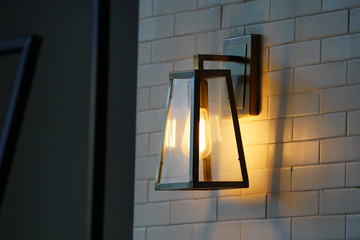 Square steel lamp tungsten/warm light on the white brick wall.