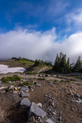 trail leading down a mountain through white fluffy clouds