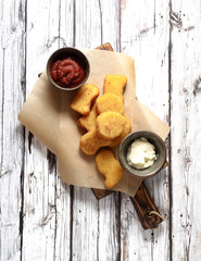 Fried chicken nuggets with white sauce and ketchup on a light wooden background. Top view.