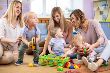 Three woman friends with toddlers playing on the floor in sitting room