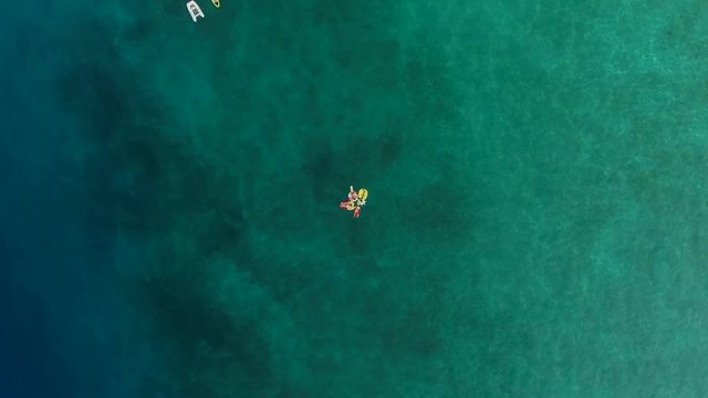 Aerial view of group holding hands on inflatable mattress on Atokos island.