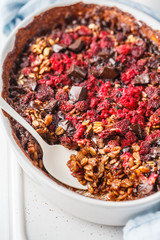 Baked oatmeal with berries and chocolate in a white dish.