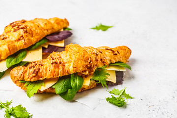 Croissants with cheese and salad on white wooden background.