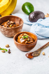 Avocado chocolate mousse with banana and pistachios in wooden bowl on white background.