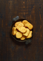 Fried chicken nuggets in a pan on a dark wooden background. Top view