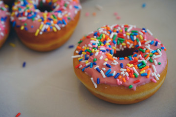 Fresh donuts with pink icing and colorful sprinkles