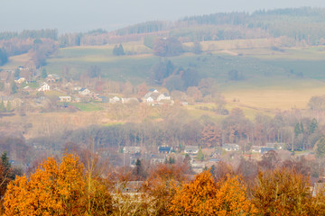 Panoramic view of Vielsalm village with valley with yellowing foliage trees covered by thick fog in background, seen from the Bec du Corbeau hill, cold autumn day in the Belgian Ardennes