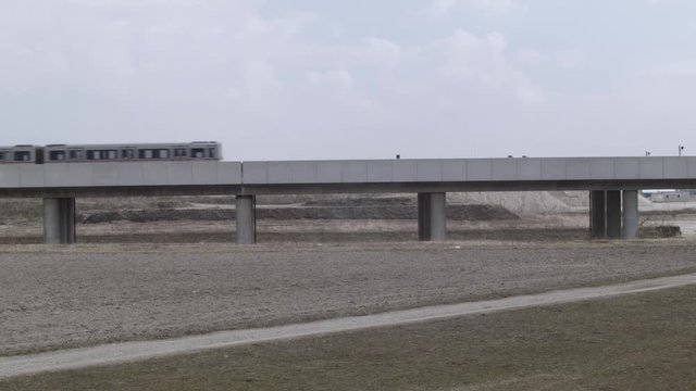 Vienna U2, Seestadt in the making - Wide shot of metro train driving through vast dry landscape