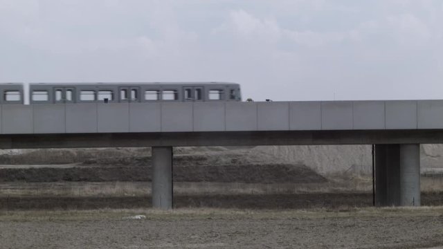 Vienna U2, Seestadt in the making - Wide shot of metro train driving through vast dry landscape