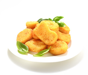 Fried chicken nuggets with basil leaves on a white background.