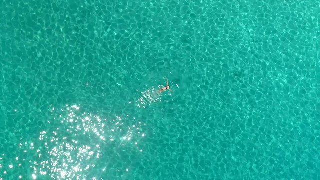 Aerial view of a woman swimming in the sea of Atokos island, Greece