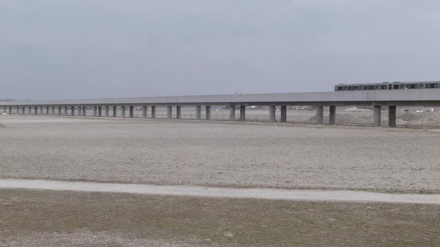 Vienna U2, Seestadt in the making - Wide shot of metro train driving through vast dry landscape