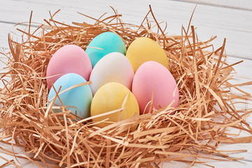 Naklejka na ściany i meble Easter background. Colorful easter eggs in paper nest on a white background, close up