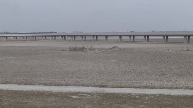 Vienna U2, Seestadt in the making - Wide shot of metro train driving through vast dry landscape