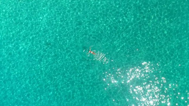 Aerial view of a woman swimming in the sea of Atokos island, Greece