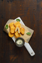 Fried chicken nuggets with white sauce and basil leaves  on a dark wooden background. Top view.