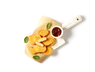 Fried chicken nuggets with ketchup and basil leaves on a white background.